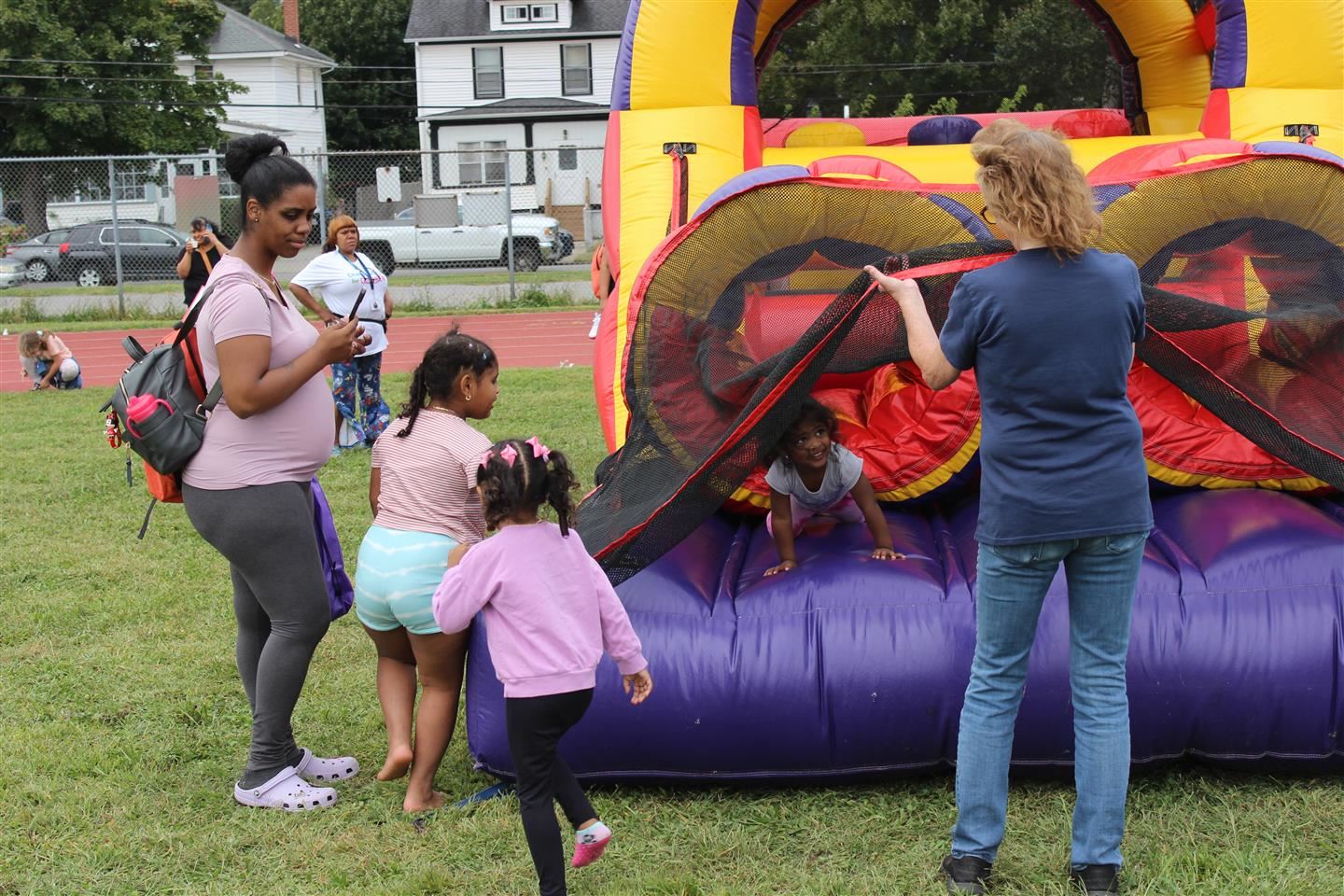 A family waits for a girl to exit an inflatable obstacle course